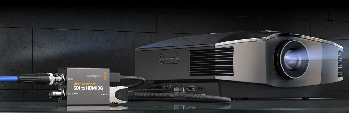 a closeup view of a modern projector positioned alongside a micro converter device the projector features a sleek design with a prominent lens while the converter connects to it with cables against a dark background digital production A close-up view of a modern projector positioned alongside a micro converter device. The projector features a sleek design with a prominent lens, while the converter connects to it with cables against a dark background.