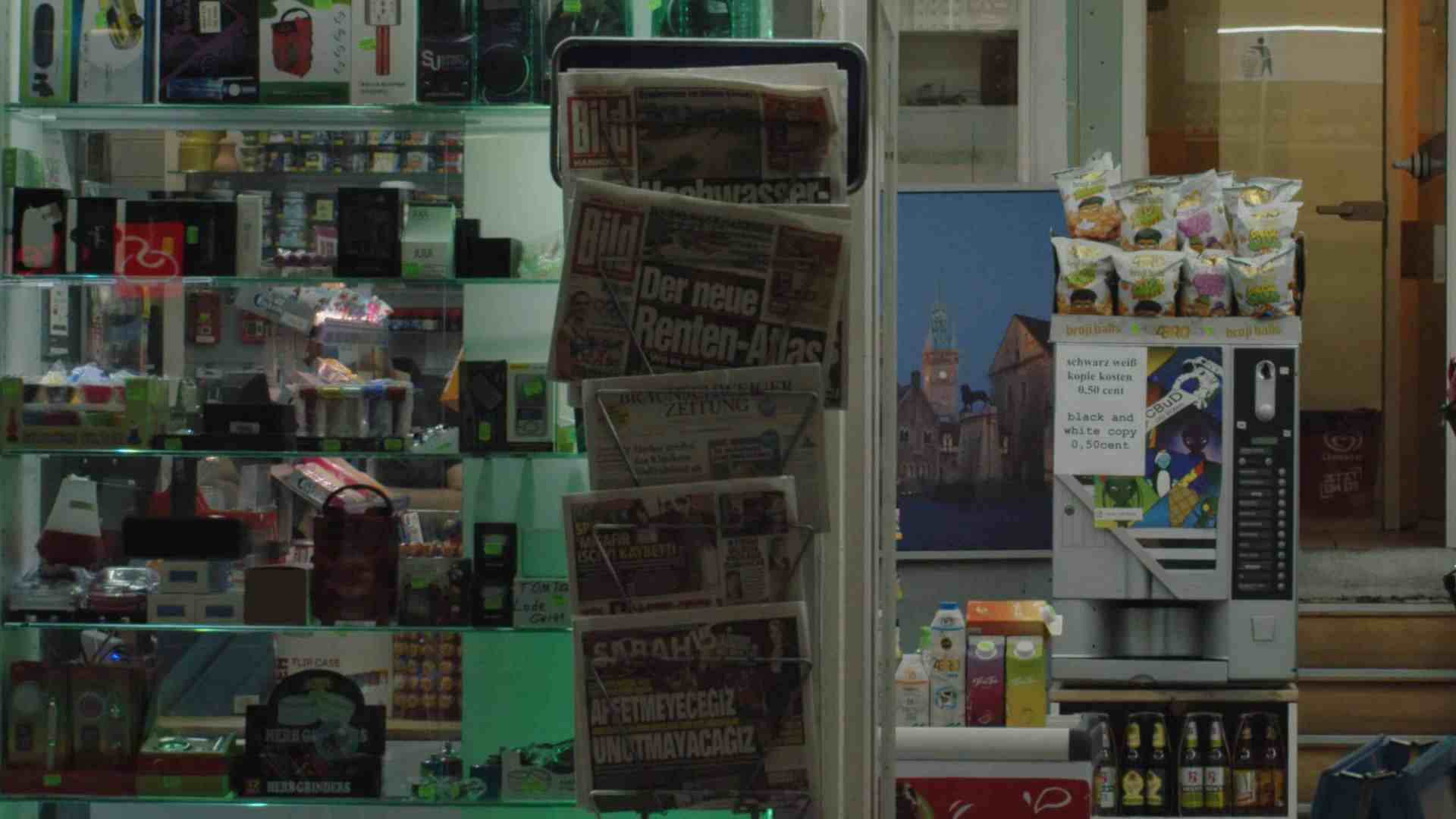a small convenience store display featuring snack packages drinks and a newspaper stand with headlines visible a vending machine is also present the interior is lit warmly and theres a picture of a building in the background digital production A small convenience store display featuring snack packages, drinks, and a newspaper stand with headlines visible. A vending machine is also present. The interior is lit warmly, and there's a picture of a building in the background.