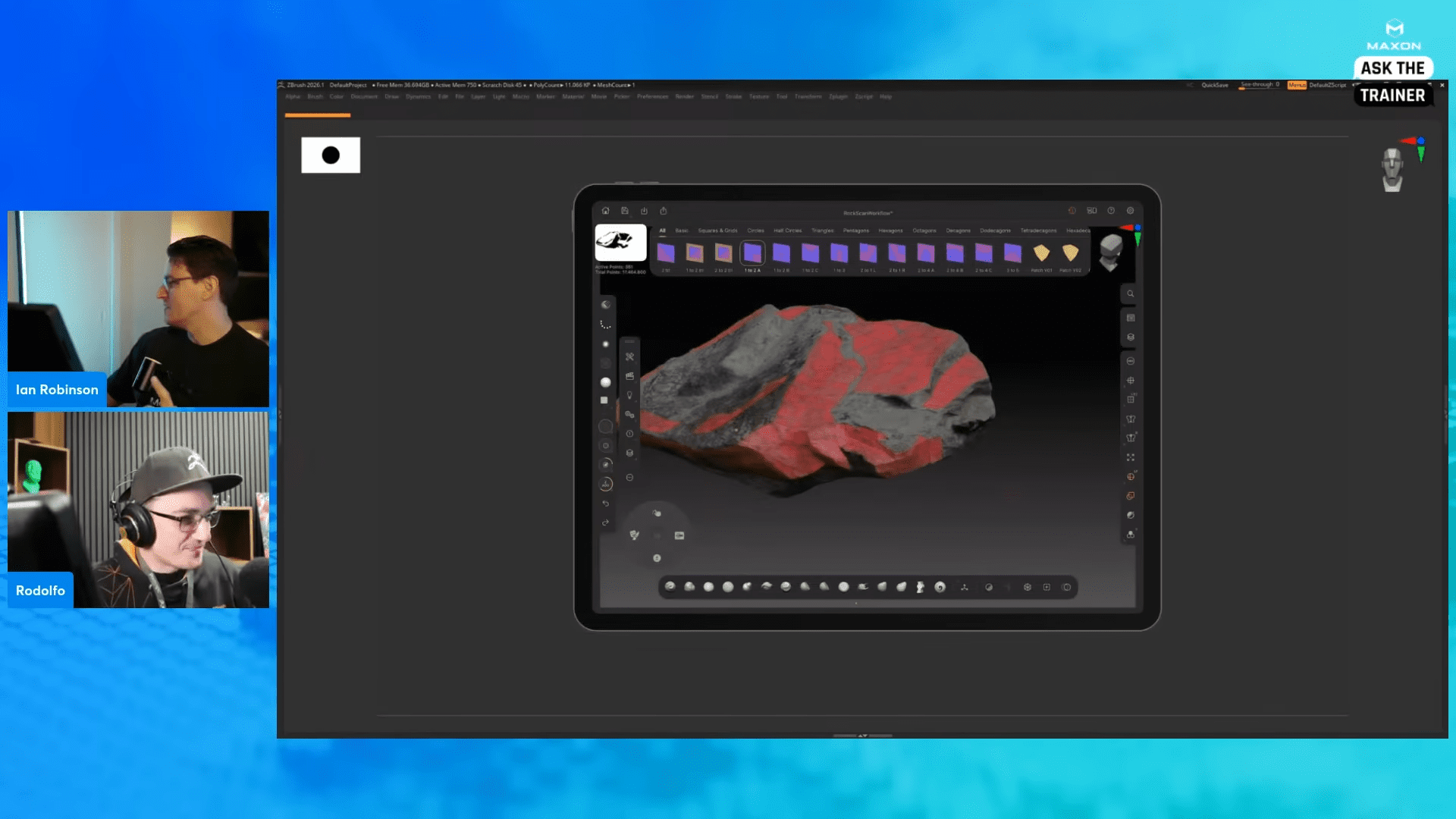 a digital workspace displaying a textured 3d rock model with red and gray colors on a tablet screen two presenters one facing the screen and the other looking towards the camera demonstrate the modeling process during a training session digital production A digital workspace displaying a textured 3D rock model with red and gray colors on a tablet screen. Two presenters, one facing the screen and the other looking towards the camera, demonstrate the modeling process during a training session.